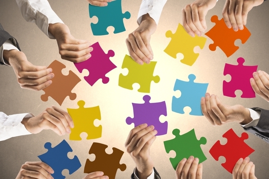 Viele Hände halten große, bunte Puzzleteile Viele Hände halten große, bunte Puzzleteile