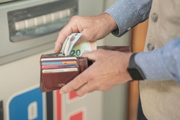 Hände sortieren Bargeld in Portemonnaie vor Geldautomat Hände sortieren Bargeld in Portemonnaie vor Geldautomat