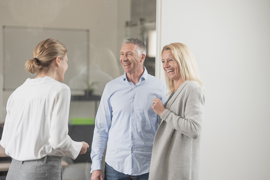 Beraterin steht lachend mit Pärchen im Flur
