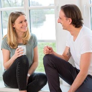 Ein Pärchen sitzt am Fenster und lächelt sich zu