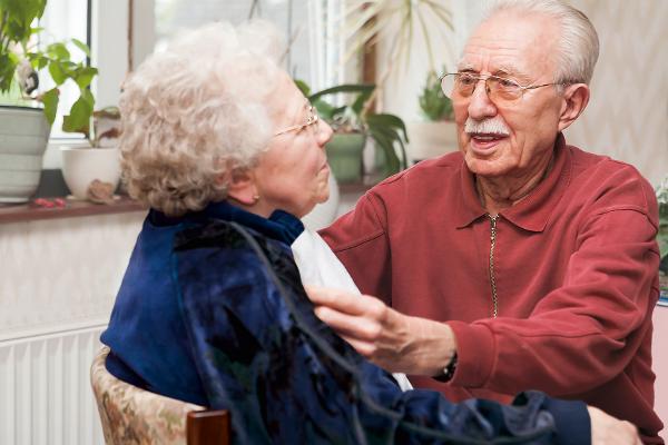 Ein aelterer Herr legt seiner Frau eine Serviette um Ein aelterer Herr legt seiner Frau eine Serviette um