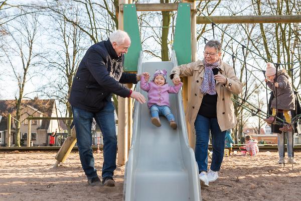 Großeltern spielen mit ihrer Enkelin auf dem Spielplatz