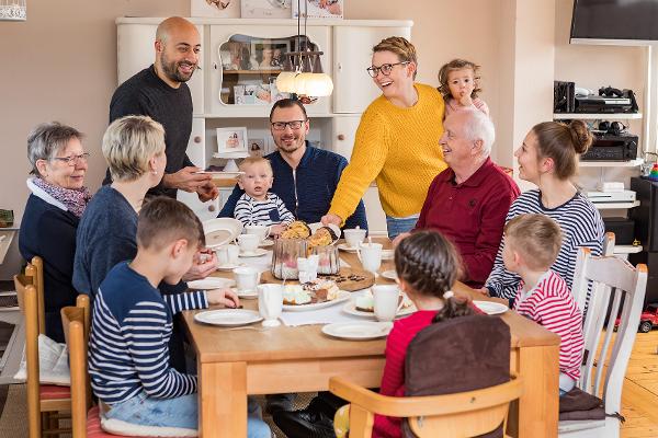 Eine große Familie sitzt am Esstisch und isst Kuchen Eine große Familie sitzt am Esstisch und isst Kuchen