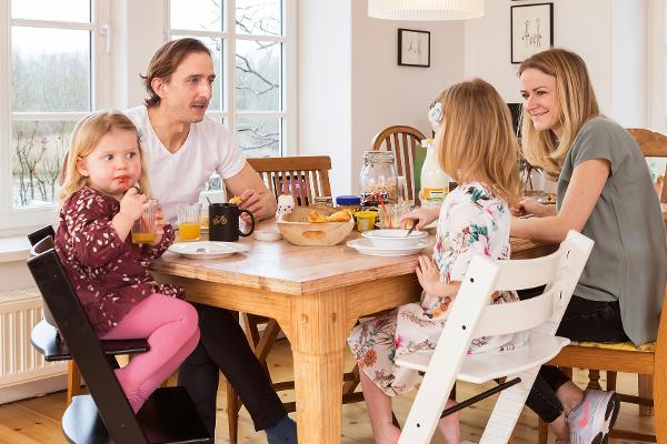 Eltern sitzen mit ihren kleinen Töchtern am Frühstückstisch