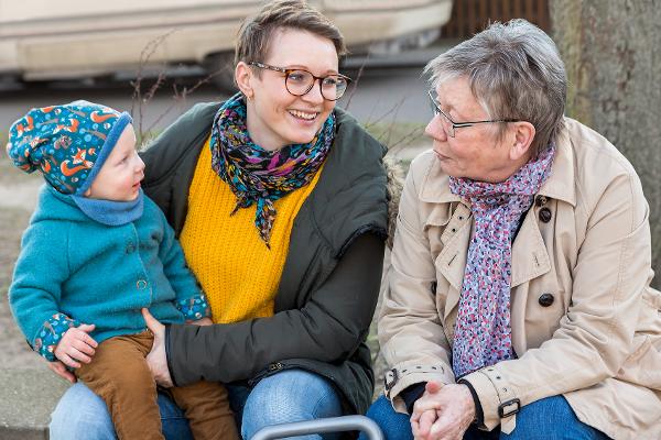 Großmutter sitzt mit Tochter und Enkelkind im Freien