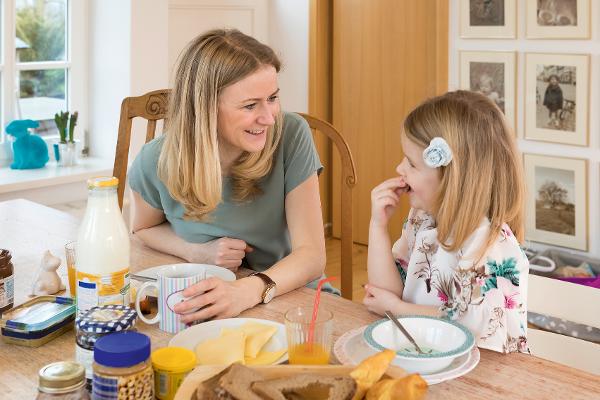 Eine Mutter sitzt mit ihrer kleinen Tochter am Frühstückstisch Eine Mutter sitzt mit ihrer kleinen Tochter am Frühstückstisch