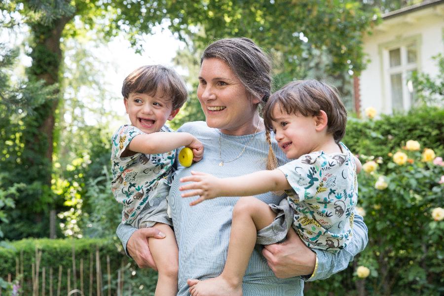 Eine Mutter trägt zwei Söhne auf dem Arm Eine Mutter trägt zwei Söhne auf dem Arm