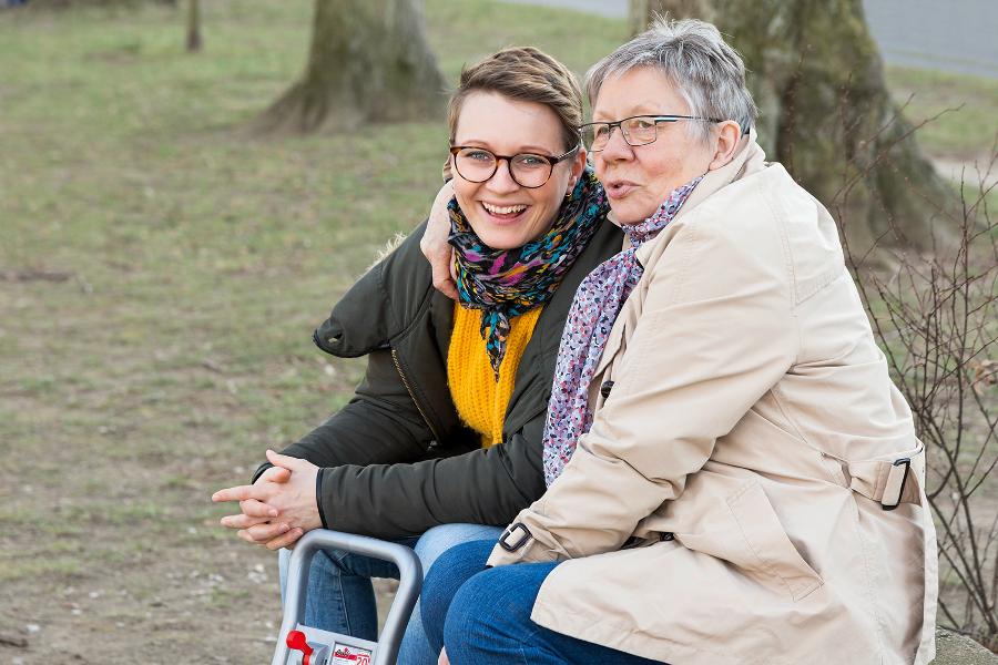 Mutter und ihre erwachsene Tochter sitzen und lachen gemeinsam Mutter und ihre erwachsene Tochter sitzen und lachen gemeinsam