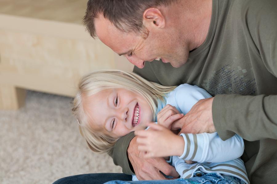 Vater kitzelt seine kleine blonde Tochter. Eng aneindergeschmiegt lachen sie zusammen. Vater kitzelt seine kleine blonde Tochter. Eng aneindergeschmiegt lachen sie zusammen.
