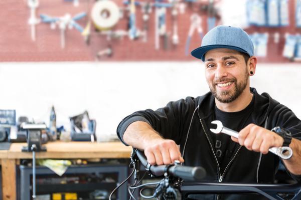 Ein junger Mann repariert ein Fahrrad in einer Werkstatt. Ein junger Mann repariert ein Fahrrad in einer Werkstatt.