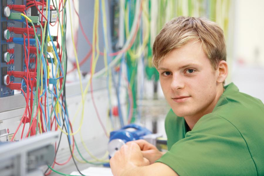 EIn junger Mann sitzt in einem Serverraum.