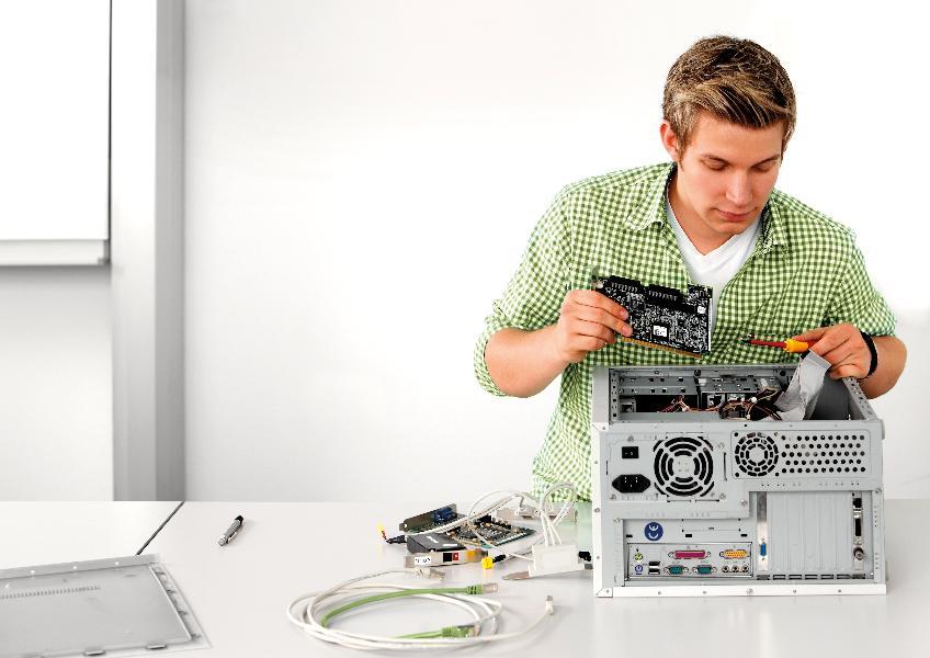 EIn junger Mann repariert einen PC. EIn junger Mann repariert einen PC.