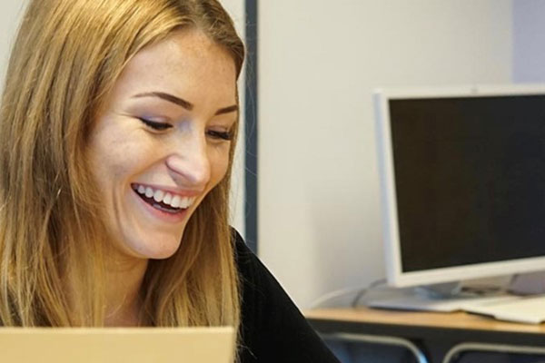 Junge Frau sitzt lachend am PC Junge Frau sitzt lachend am PC