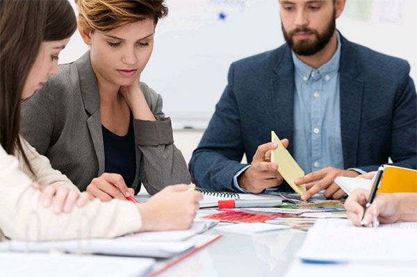 Zwei junge Frauen und ein junger Mann arbeiten am Besprechungstisch
