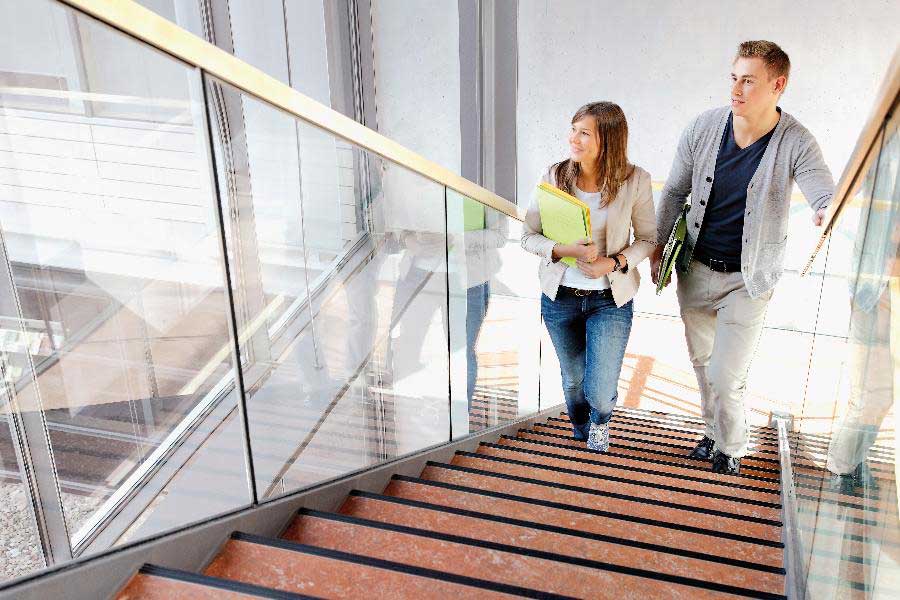 Eine junge Frau und ein junger Mann gehen eine Treppe in einem Bürogebäude hinauf.