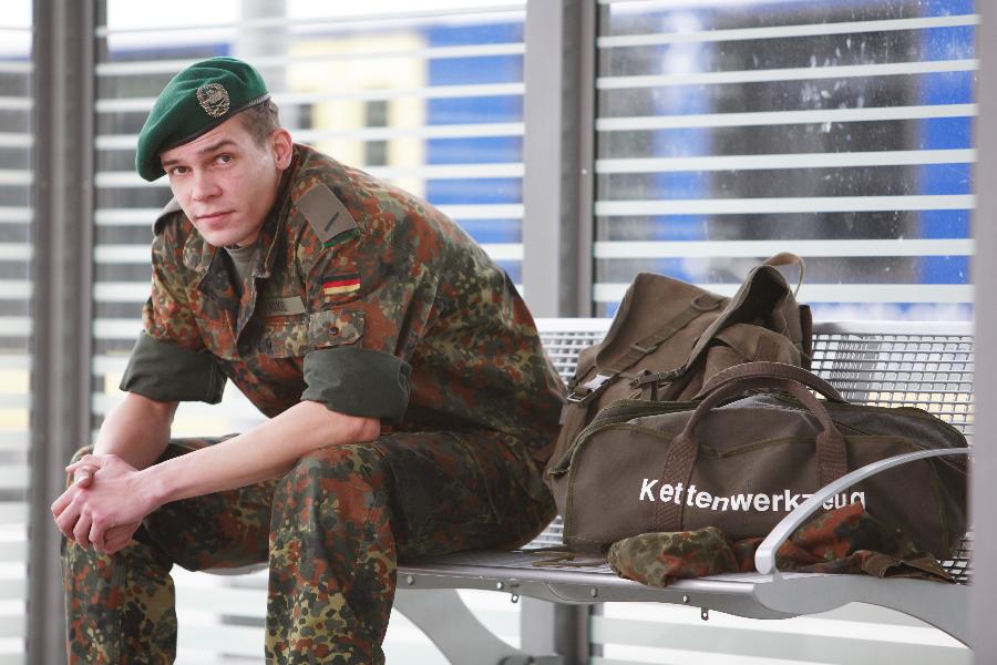 Ein junger Soldat in Uniform sitzt am Bahnhof. Ein junger Soldat in Uniform sitzt am Bahnhof.