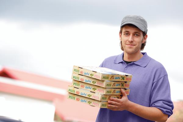 Ein Pizzalieferant hält ein paar Pizzaschachteln in den Händen Ein Pizzalieferant hält ein paar Pizzaschachteln in den Händen