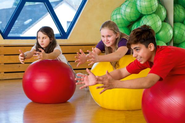 Eine Gruppe von Kindern trainiert mit Gymnastikbällen