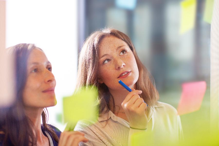 Kollegen kleben Post-its an eine Glaswand Kollegen kleben Post-its an eine Glaswand