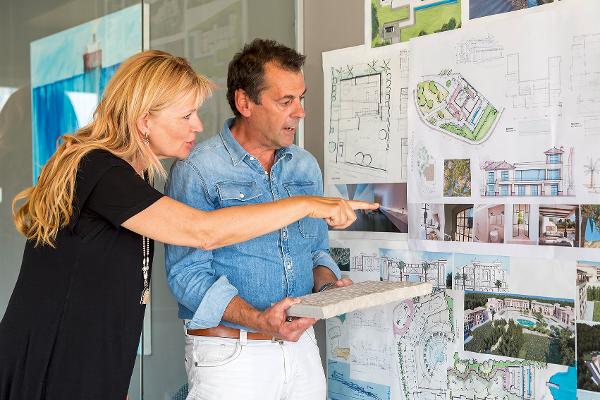 Ein Mann und eine Frau schauen auf die Planungsskizze und den Grundriss eines Hauses Ein Mann und eine Frau schauen auf die Planungsskizze und den Grundriss eines Hauses