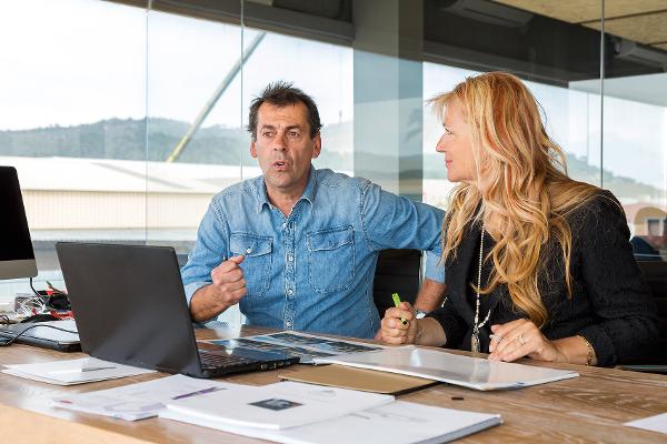 Ein Mann und eine Frau sitzen an einem Laptop und sprechen miteinander Ein Mann und eine Frau sitzen an einem Laptop und sprechen miteinander
