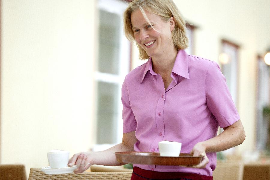 Eine Kellnerin trägt Tassen auf einem Tablett. Eine Kellnerin trägt Tassen auf einem Tablett.