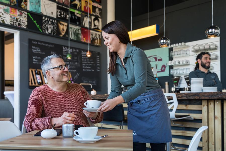 Eine Kellnerin bedient einen Gast im Café