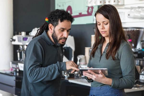 Zwei Kollegen im Café mit einem Tablet in der Hand Zwei Kollegen im Café mit einem Tablet in der Hand