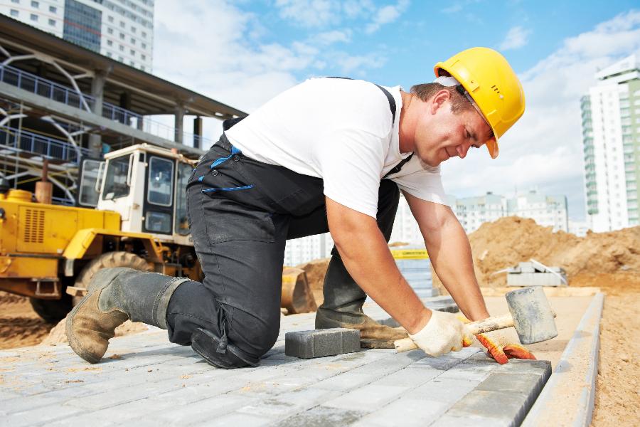 Ein Mann legt Pflstersteine auf einer Baustelle.