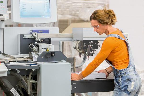 Eine Frau arbeitet an einer Maschine zur Papierverarbeitung. Eine Frau arbeitet an einer Maschine zur Papierverarbeitung.