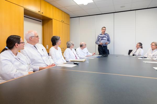 Ärzte sitzen an einem Konferenztisch und hören einem Vortrag zu