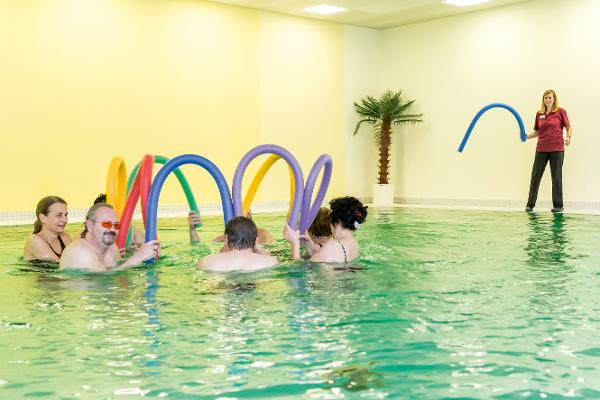 Eine Gruppe wird von einer Trainierin beim Schwimmtraining betreut Eine Gruppe wird von einer Trainierin beim Schwimmtraining betreut