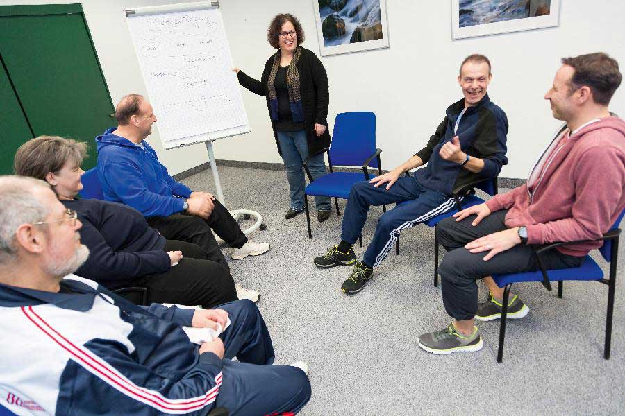 Eine Gruppe wird von einer Seminarleiterin zum Thema Stressbewältigung betreut