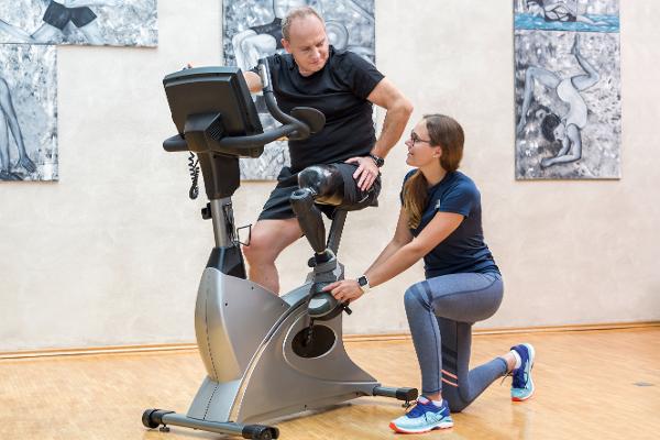 Ein Mann mit einer Beinprothese wird von einer Trainerin beim Training auf einem Heimtrainer-Fahrrad betreut Ein Mann mit einer Beinprothese wird von einer Trainerin beim Training auf einem Heimtrainer-Fahrrad betreut