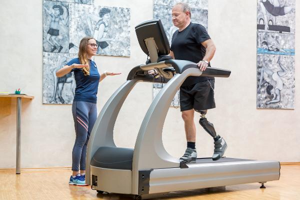 Ein Mann mit einer Beinprothese wird von einer Trainerin beim Training auf einem Laufband betreut Ein Mann mit einer Beinprothese wird von einer Trainerin beim Training auf einem Laufband betreut