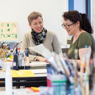 Zwei Frauen unterhalten sich in einer Kreativwerkstatt Zwei Frauen unterhalten sich in einer Kreativwerkstatt