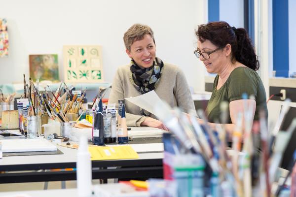 Zwei Frauen unterhalten sich in einer Kreativwerkstatt