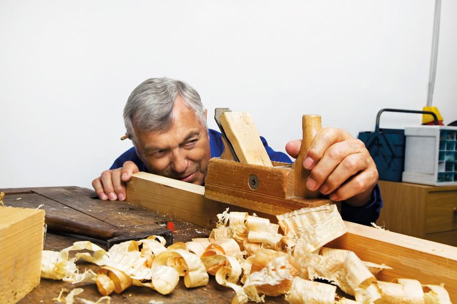 Ein älterer Mann hobelt Holz. Ein älterer Mann hobelt Holz.