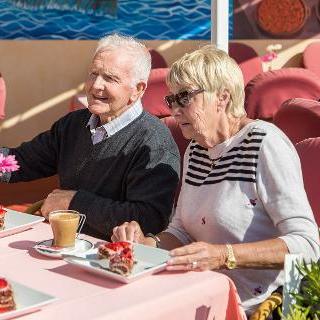 Zwei Senioren sitzen in einem Café am Tisch, sie esse Kuchen und trinken Kaffee
