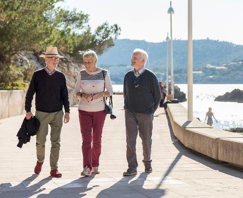 Drei Senioren bei einem Spaziergang an einer Strandpromenade