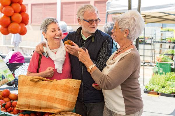 Drei Senioren kaufen Gemüse an einem Marktstand