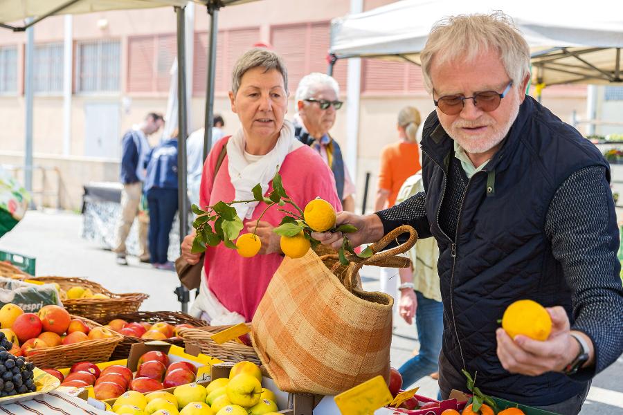 Zwei Senioren kaufen Zitronen an einem Marktstand
