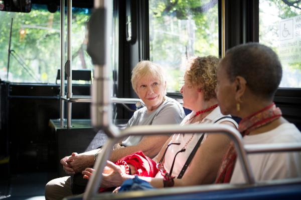 Eine Seniorin unterhält sich im Bus mit anderen Fahrgästen Eine Seniorin unterhält sich im Bus mit anderen Fahrgästen
