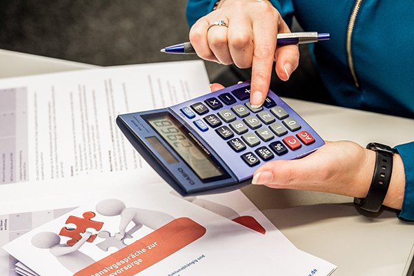 Hände halten einen blauen Taschenrechner und Finger tippen Zahlen ein. Hände halten einen blauen Taschenrechner und Finger tippen Zahlen ein.