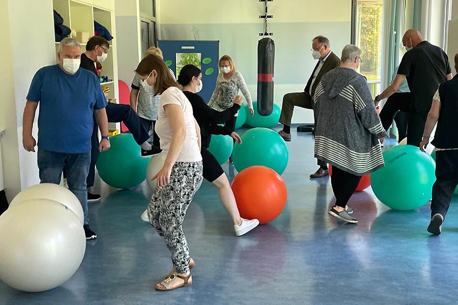 Zusammen mit den Rehabilitanden bewegt der niedersächsische Ministerpräsident Stephan Weil einen Gymnastikball durch den Übungsraum. Zusammen mit den Rehabilitanden bewegt der niedersächsische Ministerpräsident Stephan Weil einen Gymnastikball durch den Übungsraum.