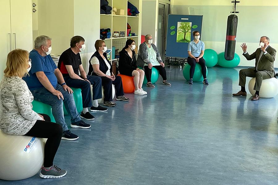 Der niedersächsische Ministerpräsudent Stephan Weil sitzt auf einem weißen Gymnastikball und spricht gestikulierend mit den gegenüber sitzenden Rehabilitanden. Der niedersächsische Ministerpräsudent Stephan Weil sitzt auf einem weißen Gymnastikball und spricht gestikulierend mit den gegenüber sitzenden Rehabilitanden.