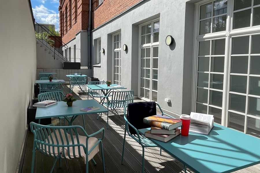 Zweigbibliothek Rohrdamm: Blick auf die Terasse mit türlisfarbenen Tischen, auf denenBücher liegen Zweigbibliothek Rohrdamm: Blick auf die Terasse mit türlisfarbenen Tischen, auf denenBücher liegen