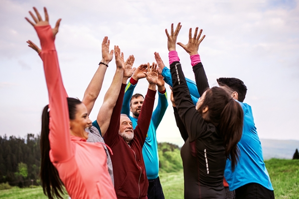 Sportgruppe, die zusammen steht und die Hände in die Luft streckt Sportgruppe, die zusammen steht und die Hände in die Luft streckt