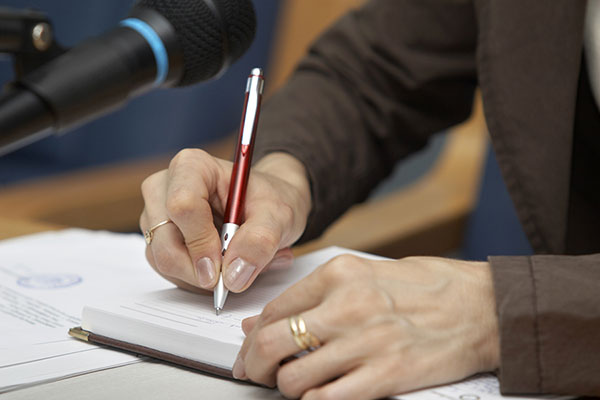Eine Person sitzt in einer Konferenz und macht sich Notizen. Eine Person sitzt in einer Konferenz und macht sich Notizen.
