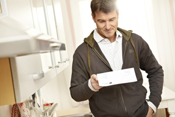 Mann hält ein Papier in der Hand und blickt darauf Mann hält ein Papier in der Hand und blickt darauf